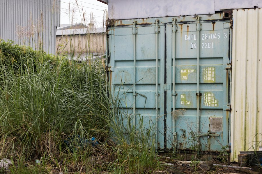 Shipping container on open ground with tall grass